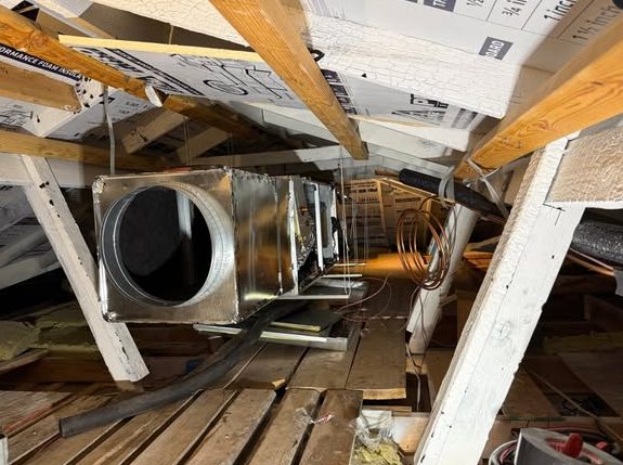 New sheet metal plenum and duct trunk being installed in an attic